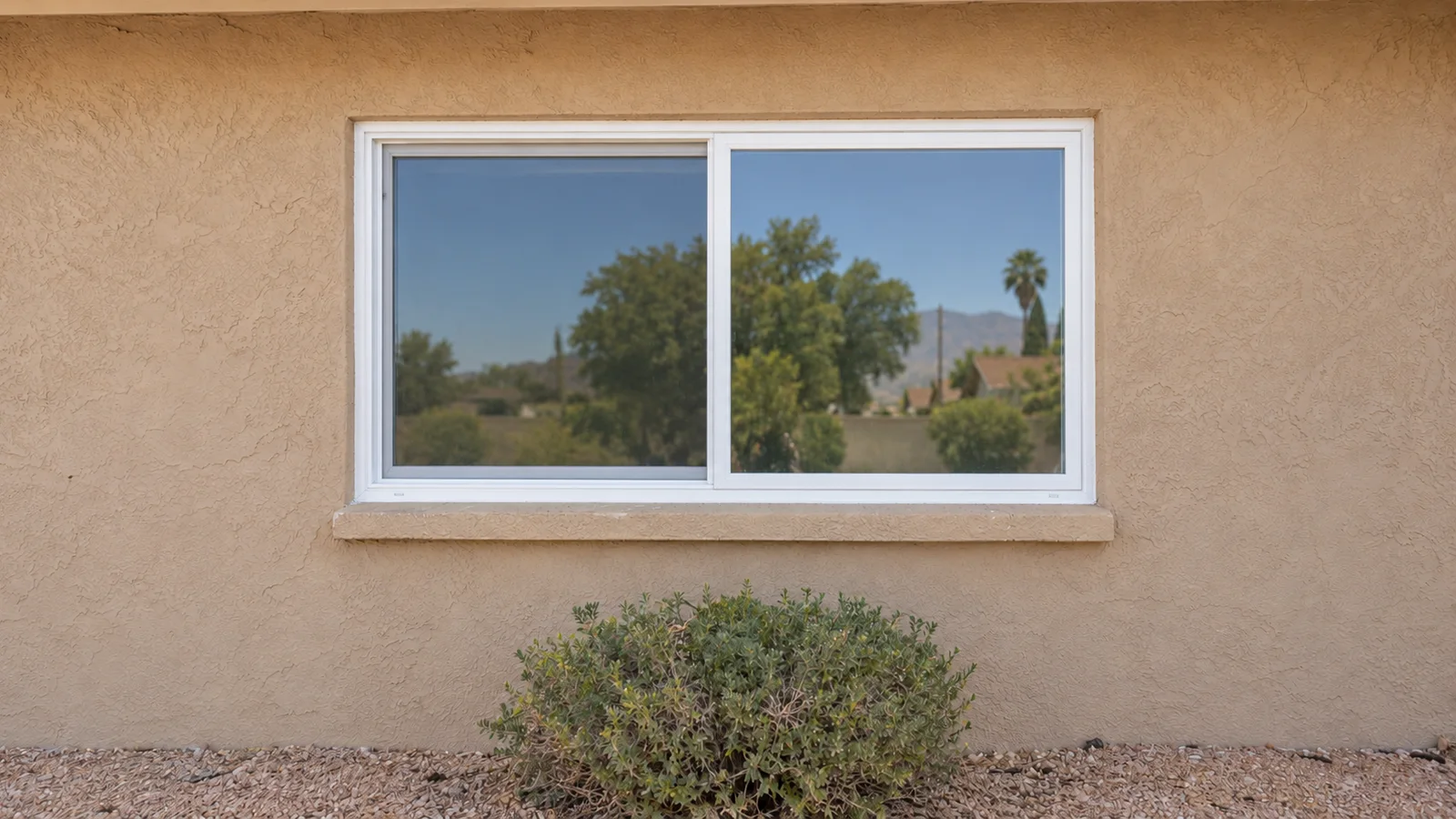 New white vinyl sliding window in the same stucco opening with clear glass and clean caulk