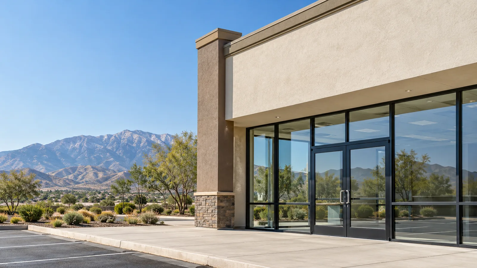 Single-storey stucco storefront with black aluminum framing, large glass panes and glass double doors